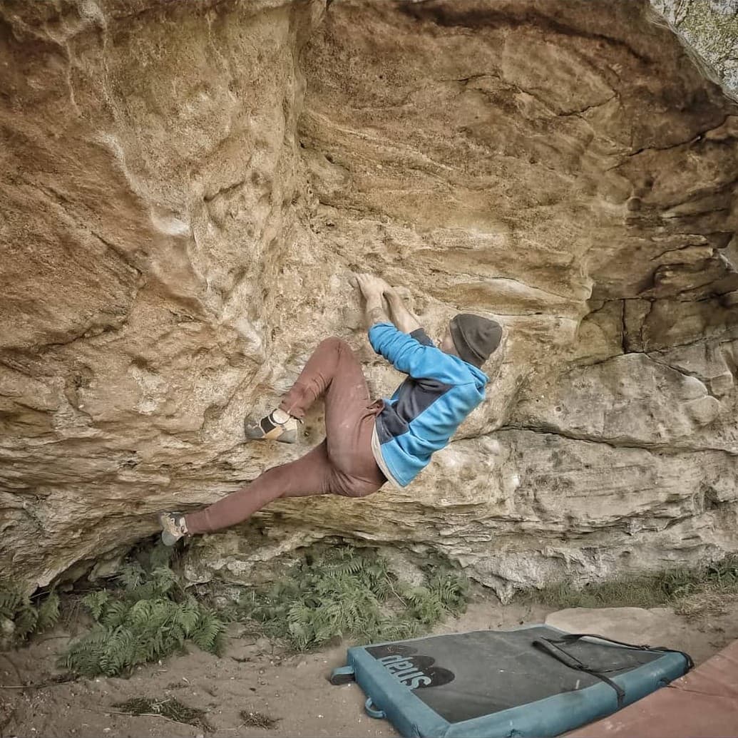 Carl Donnelly, founder and registered physiotherapist, climbing a rock outdoors